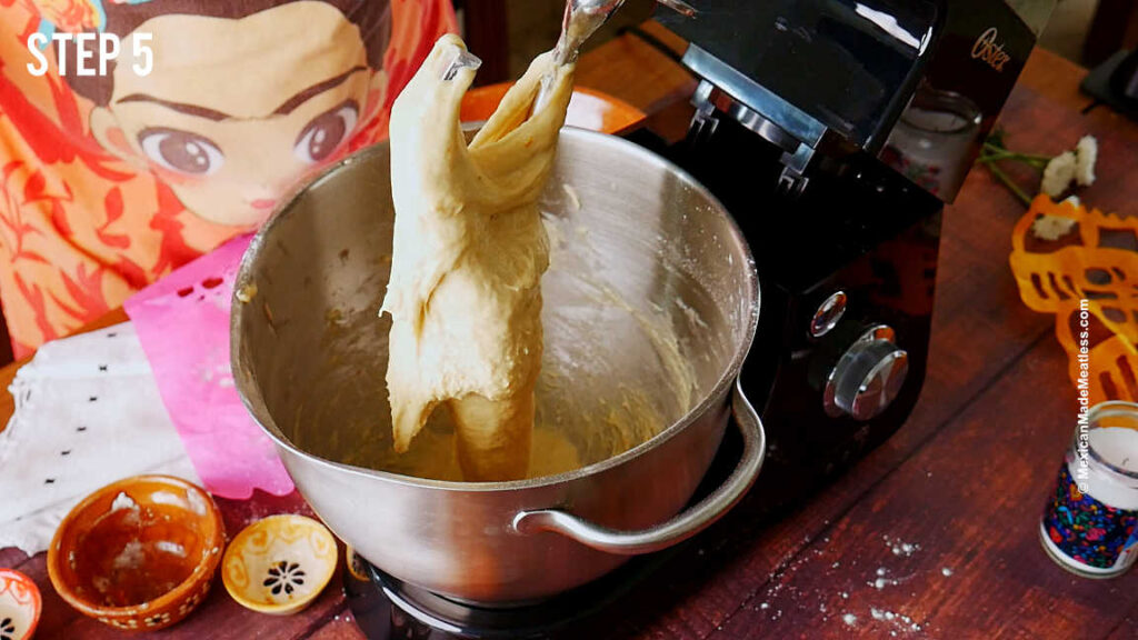 Pan de muerto dough being kneaded in a stand mixer.