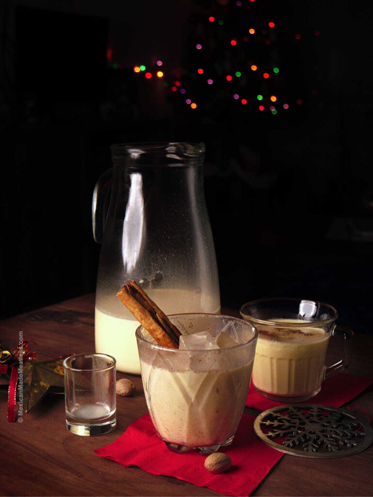 Two glasses and a glass pitcher filled with homemade eggnog recipe. 