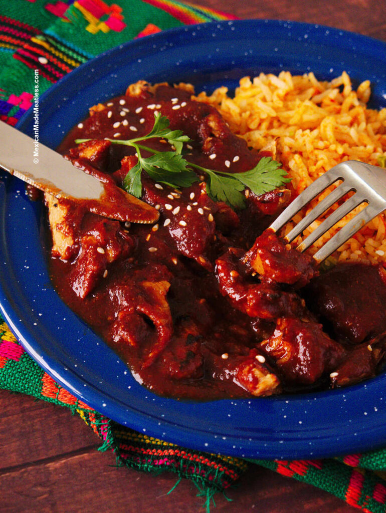 Red mole cooked without chocolate served over vegetables and Mexican rice.