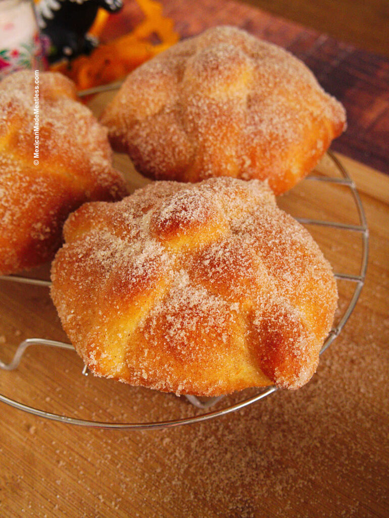 Baked vegan pan de muerto brushed with melted butter and coated with a sugar and cinnamon mixture.