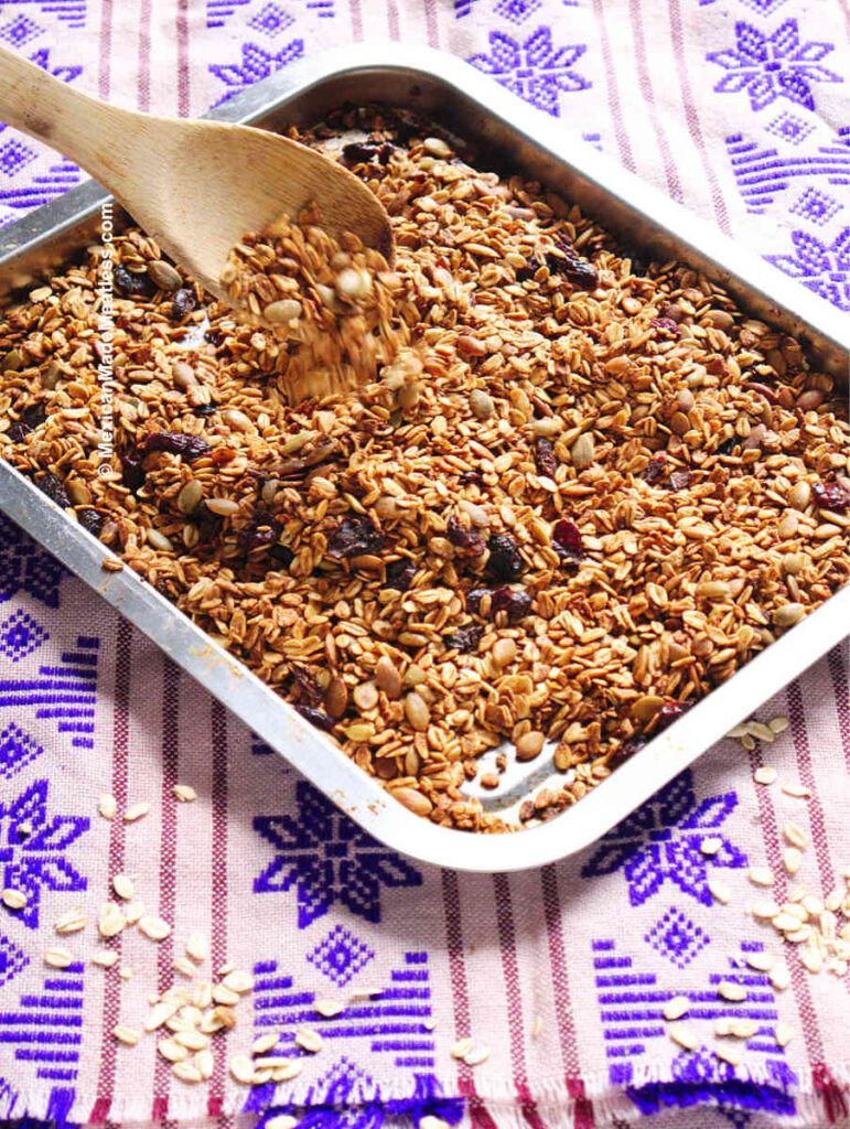 Baked Mexican granola being mixed on a cookie sheet.