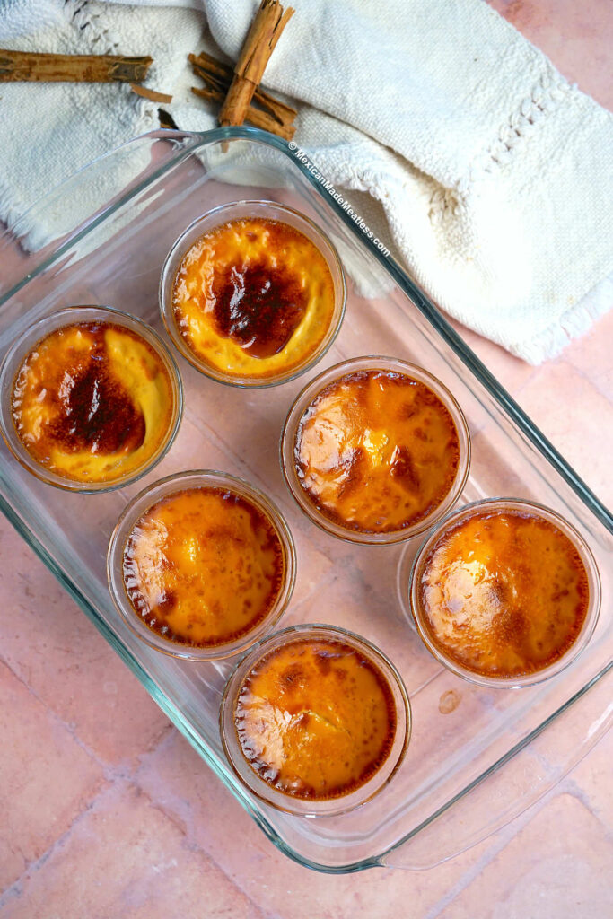 Baked jericalla Mexican custard in small individual flan molds and cooling on the table.