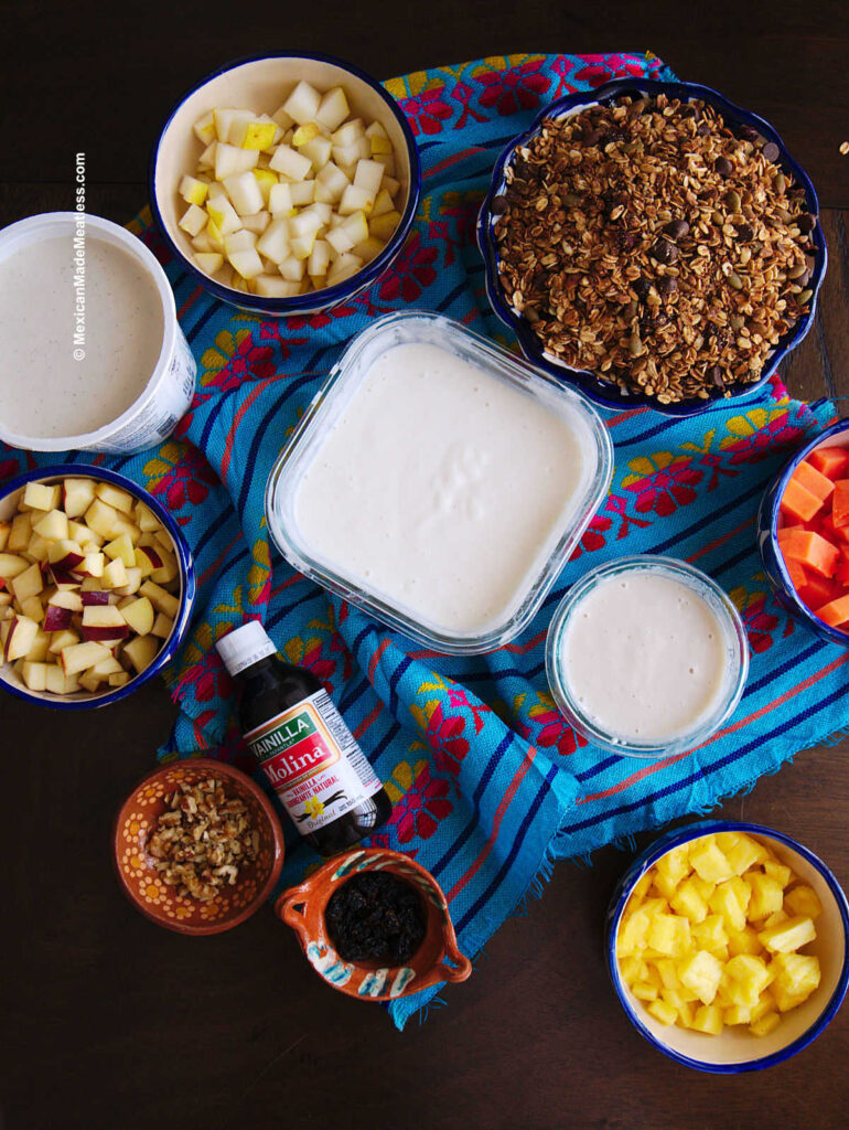 Small bowls filled with the ingredients needed to make Mexican bionico fruit salad. 