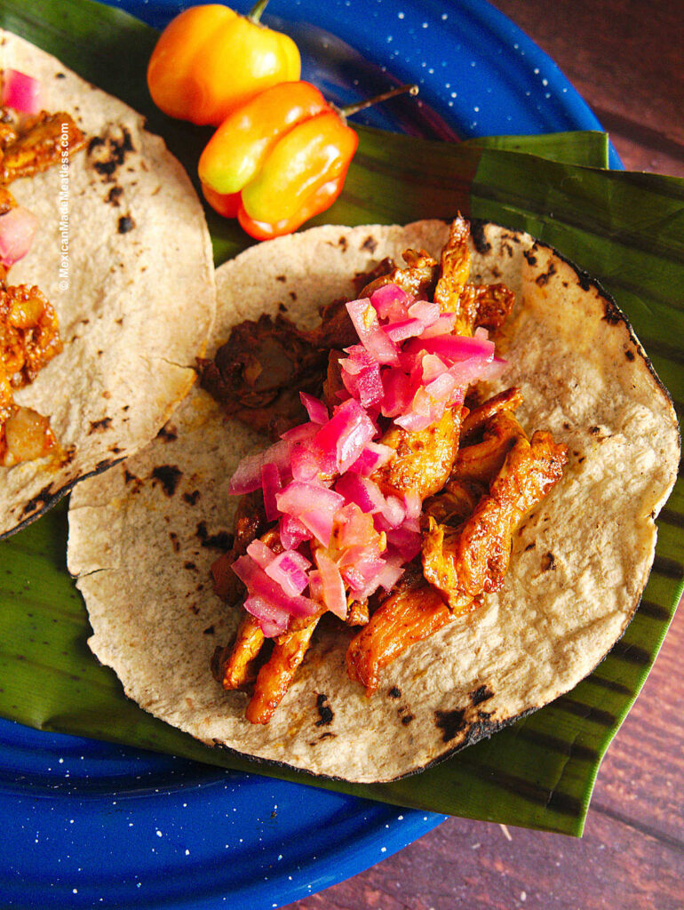 Once corn flour tortilla taco filled with plantbased cochinita pibil made with oyster mushrooms and topped with chopped pickled red onion.