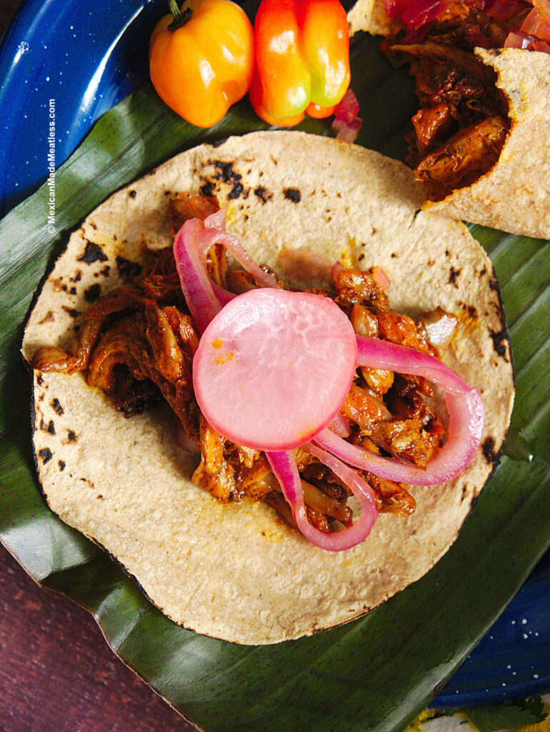 One corn tortilla filled with cochinita pibil made from mushrooms and topped with pickled onions. 