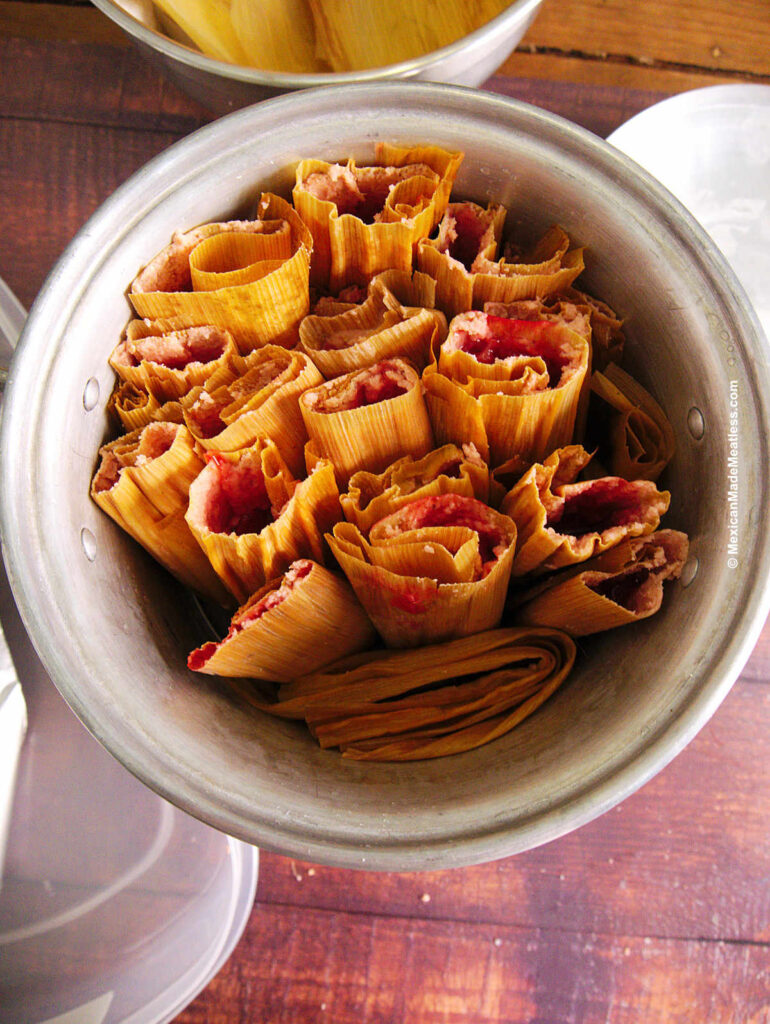 Rolled up strawberry tamales inside a tamalera steamer pot ready to be cooked.