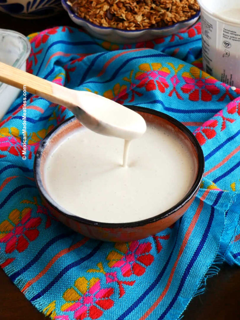 Mixing yogurt, Mexican crema and sweetened condensed milk in a brown bowl. 