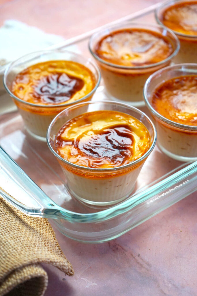 Jericallas or Mexican custard dessert inside small glass ramekins inside a glass baking dish.