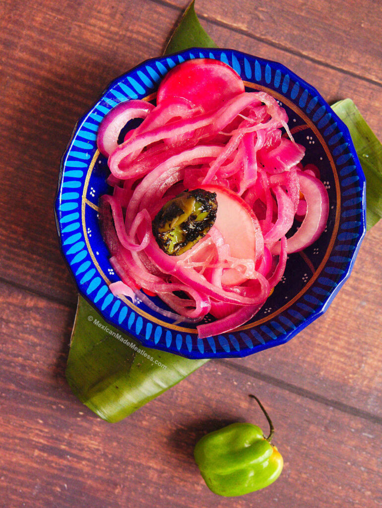 Small blue bowl filled with Mexican pickled red onions for tacos. 
