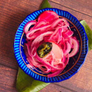 Small blue bowl filled with Mexican pickled red onions for tacos.