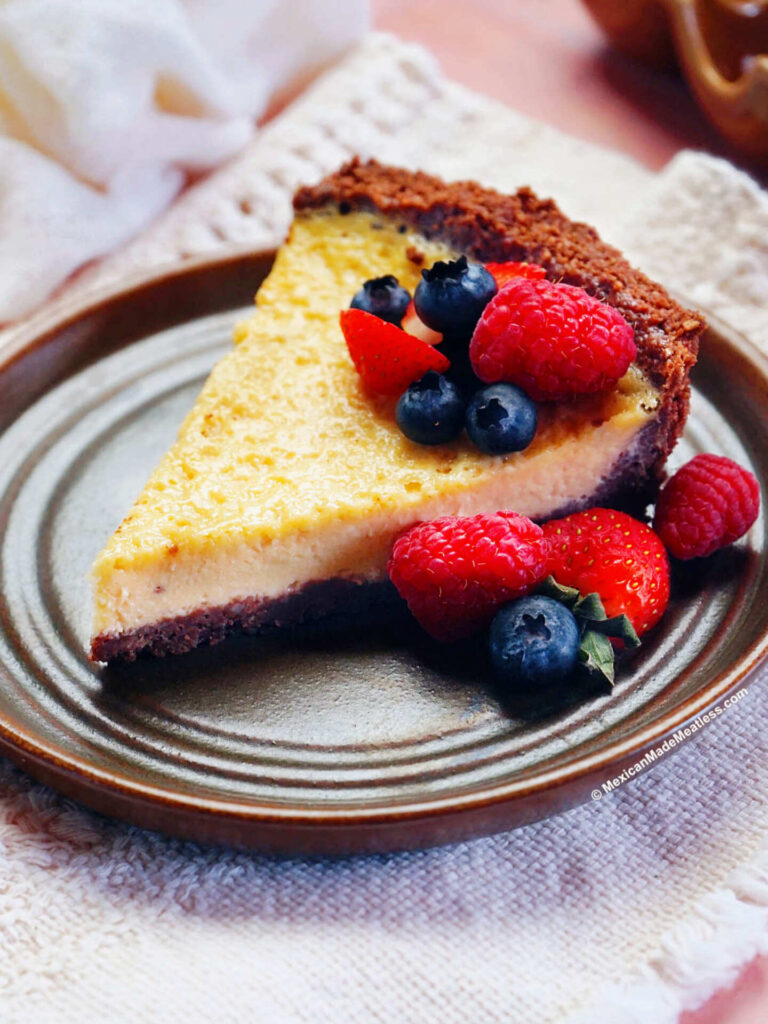 A slice of Mexican cheesecake made with a chocolate crust and some blueberries, strawberries and raspberries on top.