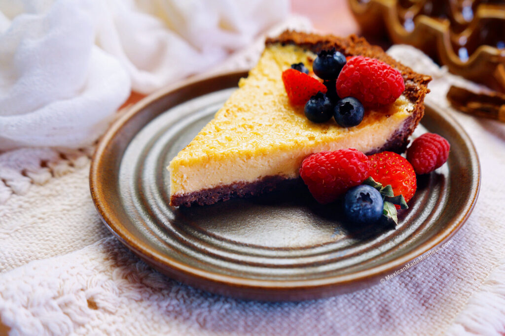 A slice of Mexican cheesecake called pay de queso on a brown plate with fresh berries. 