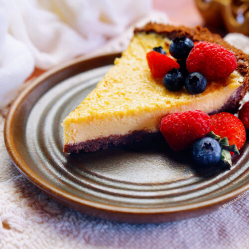 A slice of Mexican cheesecake called pay de queso on a brown plate with fresh berries.