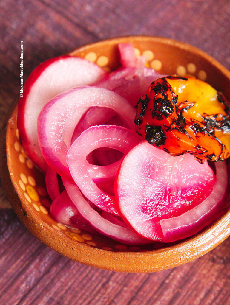 A small bowl filled with pickled red onions and habanero pepper used for cochinita pibil tacos. 