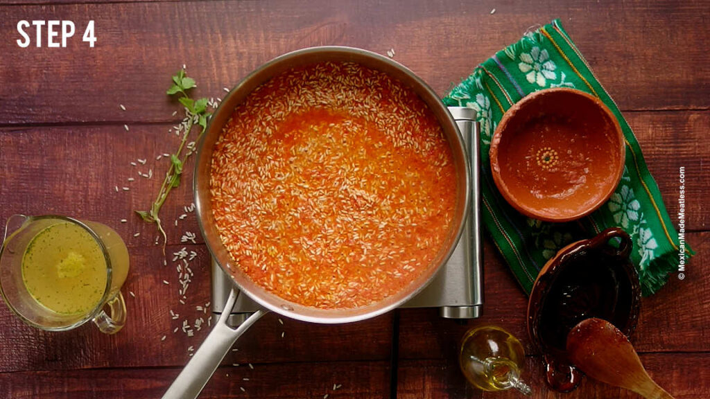 Cooking arroz rojo with homemade tomato sauce in a stainless steel pan. 