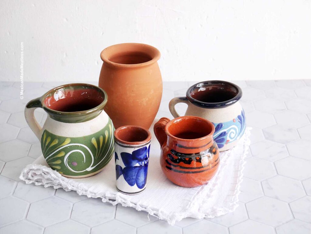 Five different barro cups and mugs sitting on a counter.