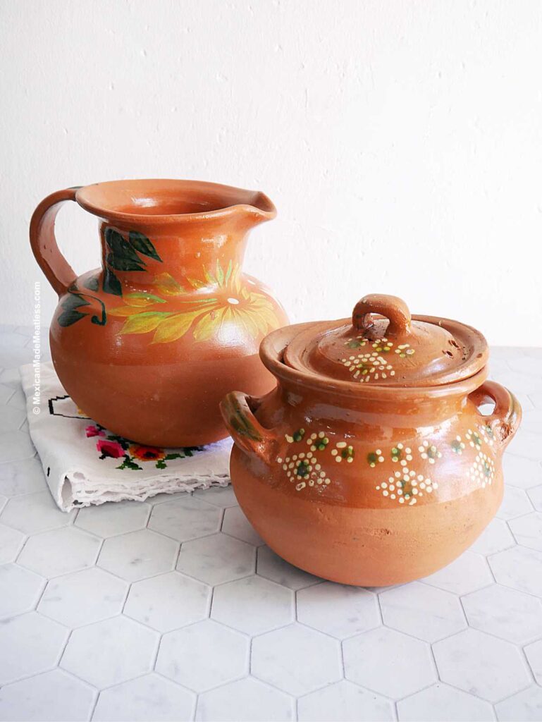 Mexican barro pot and pitcher on a white marble honeycomb countertop.