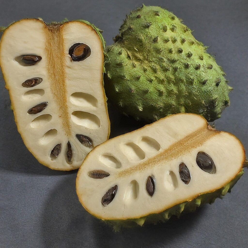 An AI generated image by Gemini of a Guanabana sliced in half and another left whole on a grey table.
