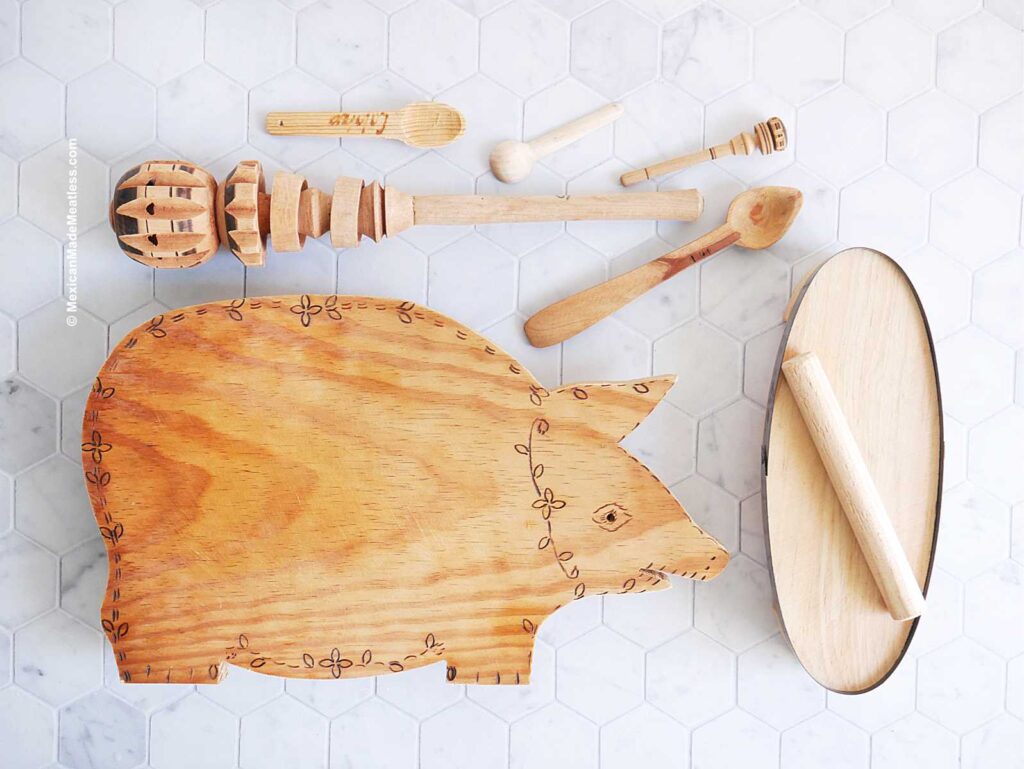 Mexican wood utensils: a pig shaped cutting board, spoons, chocolate frother and a mold for making huaraches.
