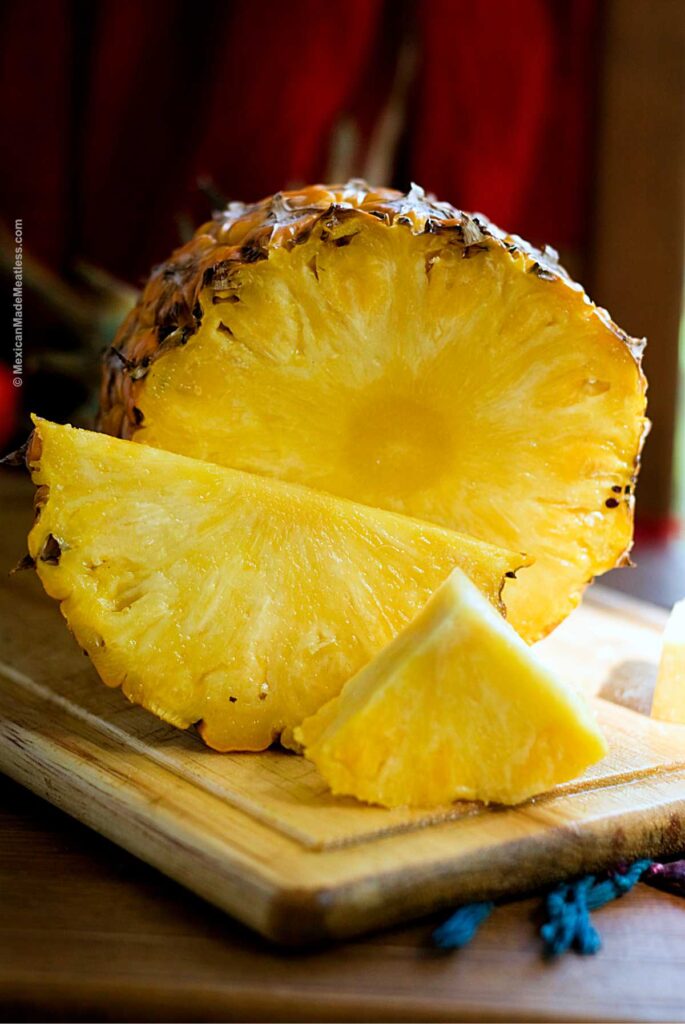 A sweet yellow Mexican pineapple sliced on a cutting board.