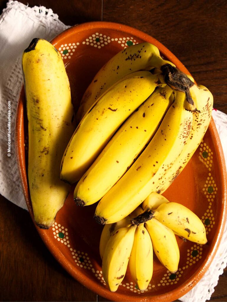 A Mexican earthenware bowl with one plantain, six regular bananas and a small bunch of 7 yellow Manzano bananas.