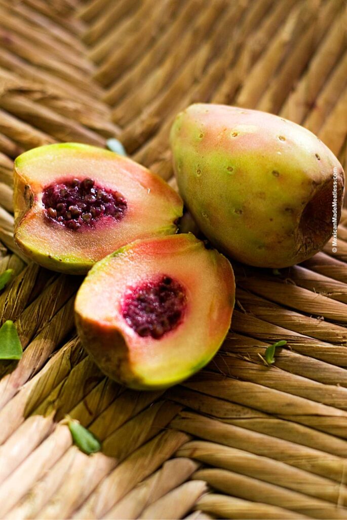 Two xoconostle or sour prickly pear fruits on a straw matt.