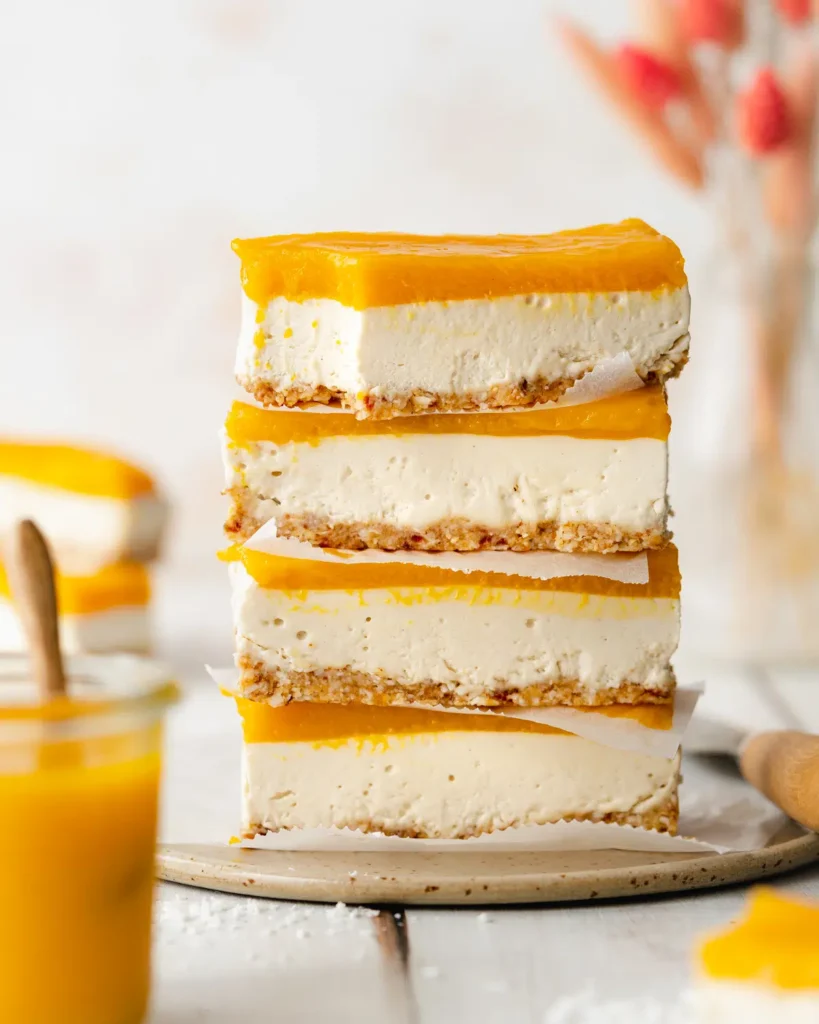 A stack of four slices of vegan mango cheesecake.