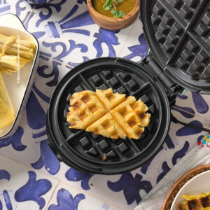 Delicious bean tamale waffle with salsa, on the side and extra uncooked tamales off to the other side.